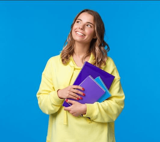 Estudante sorrindo segurando cadernos